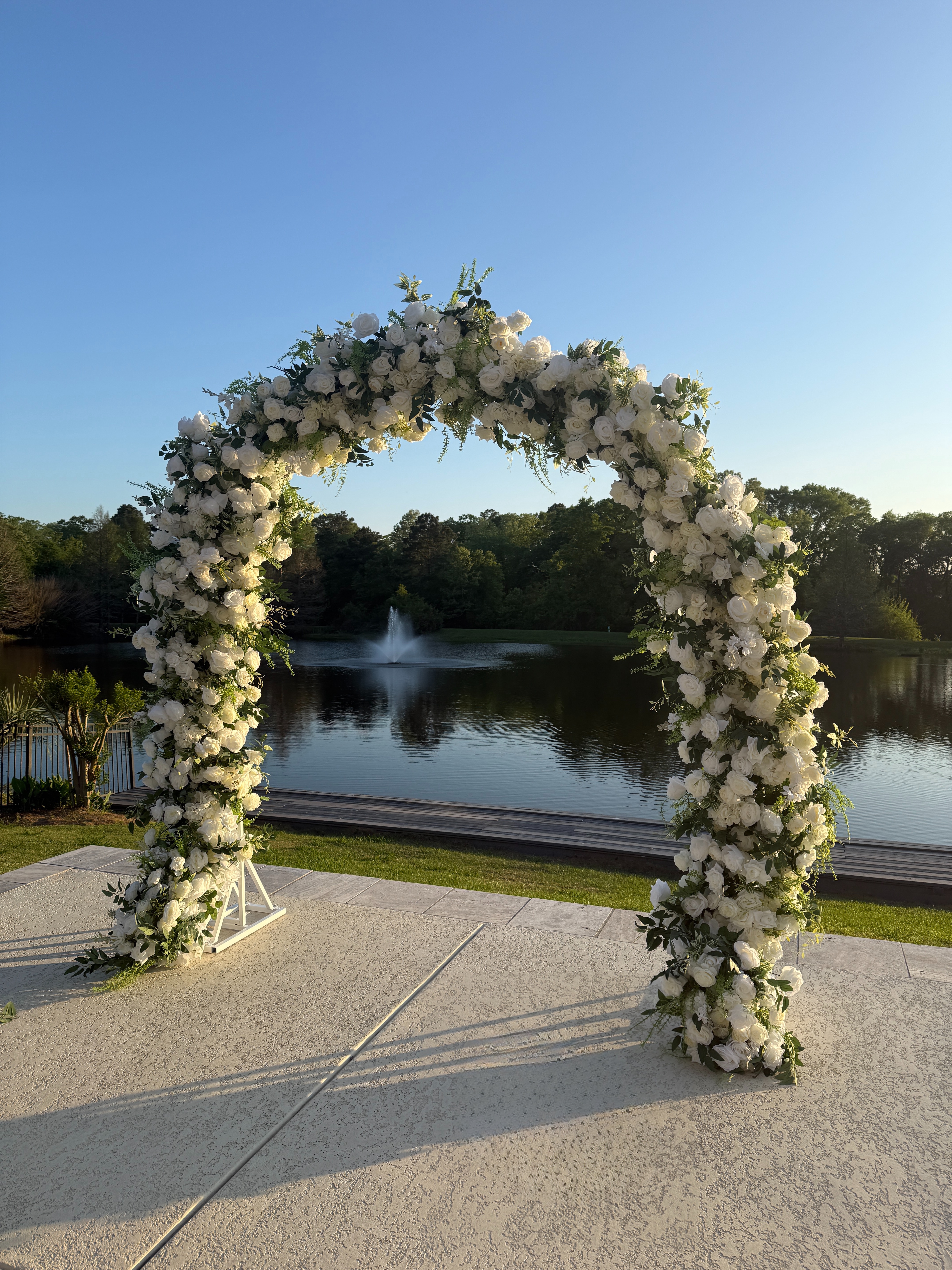 Floral arch at golden hour with lake fountain